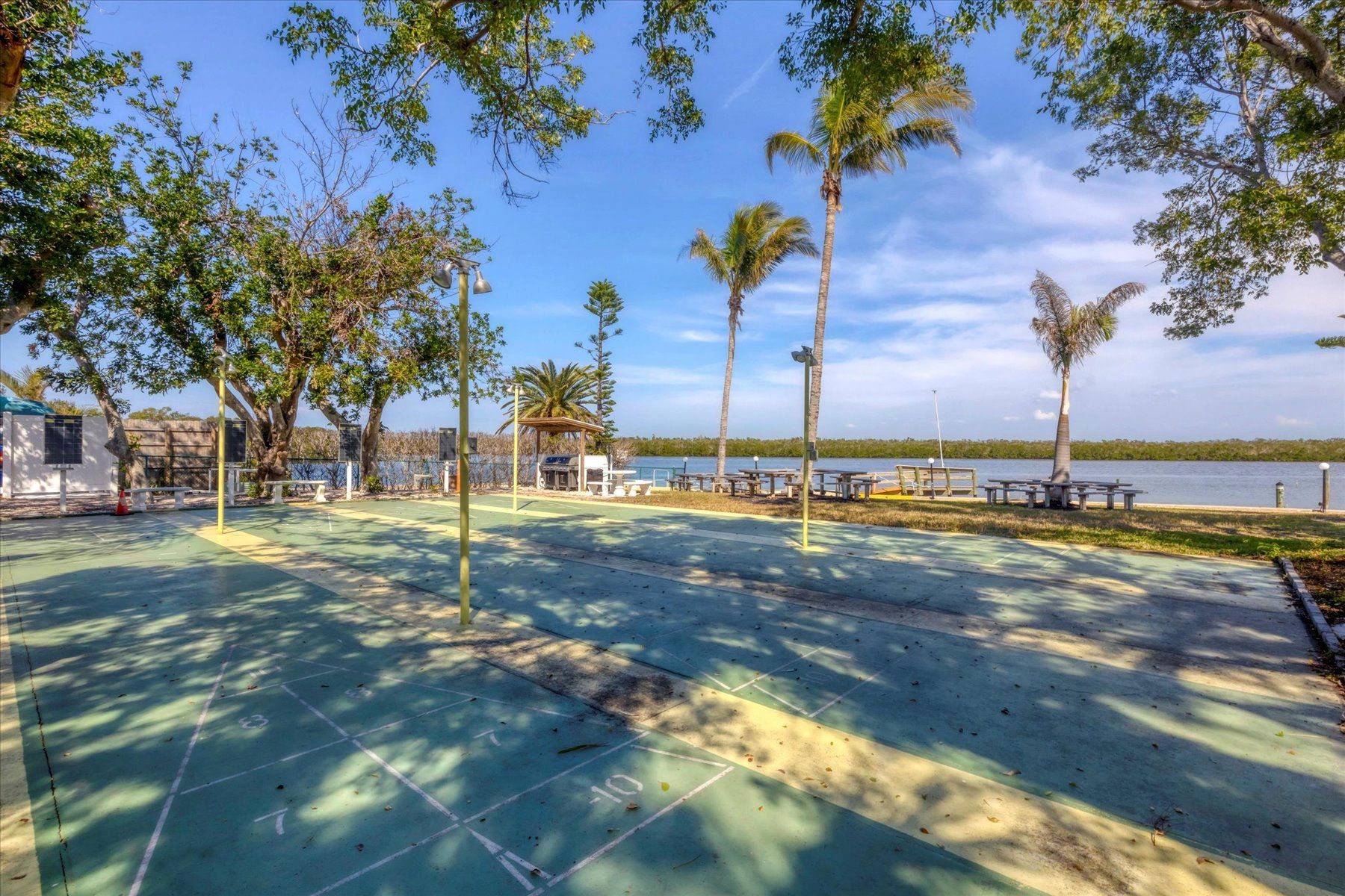 Um parque com mesas de piquenique, parquinho infantil e vista para um lago.
