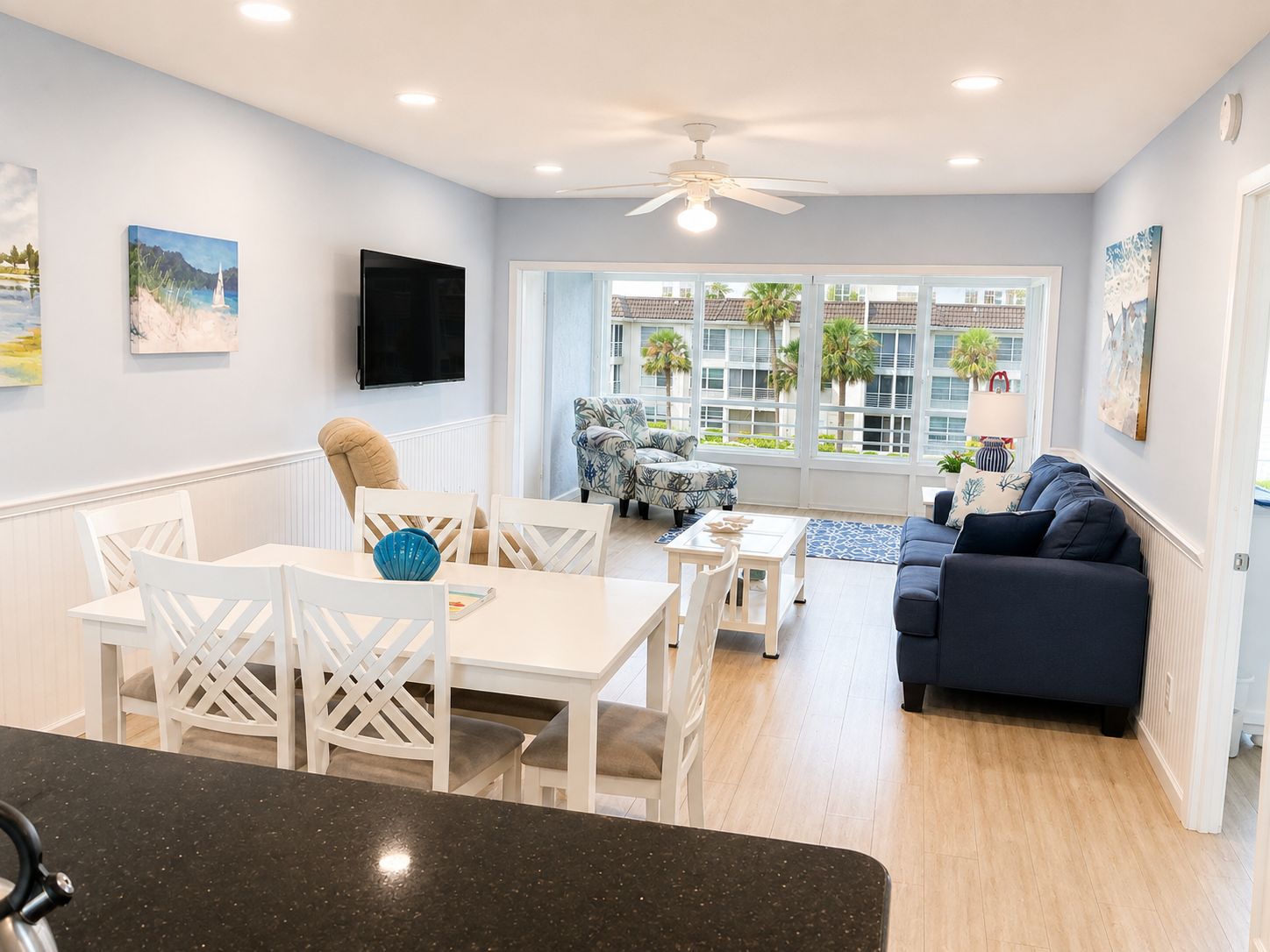 A modern living room with a dining area, a sofa, and a TV mounted on the wall.