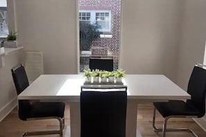 A dining area with a white table, black chairs, and potted plants. - Luxurious 4-bedroom house in charming neighborhood close to downtown Greensboro. (Greensboro)
