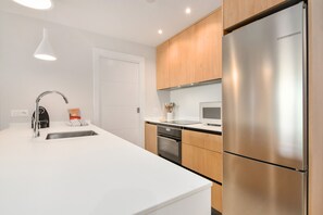 A modern kitchen with a stainless steel refrigerator, white cabinetry, and a built-in oven. - Los Colibríes by H - Isla Canela Golf GLHC7023P98 (Ayamonte)