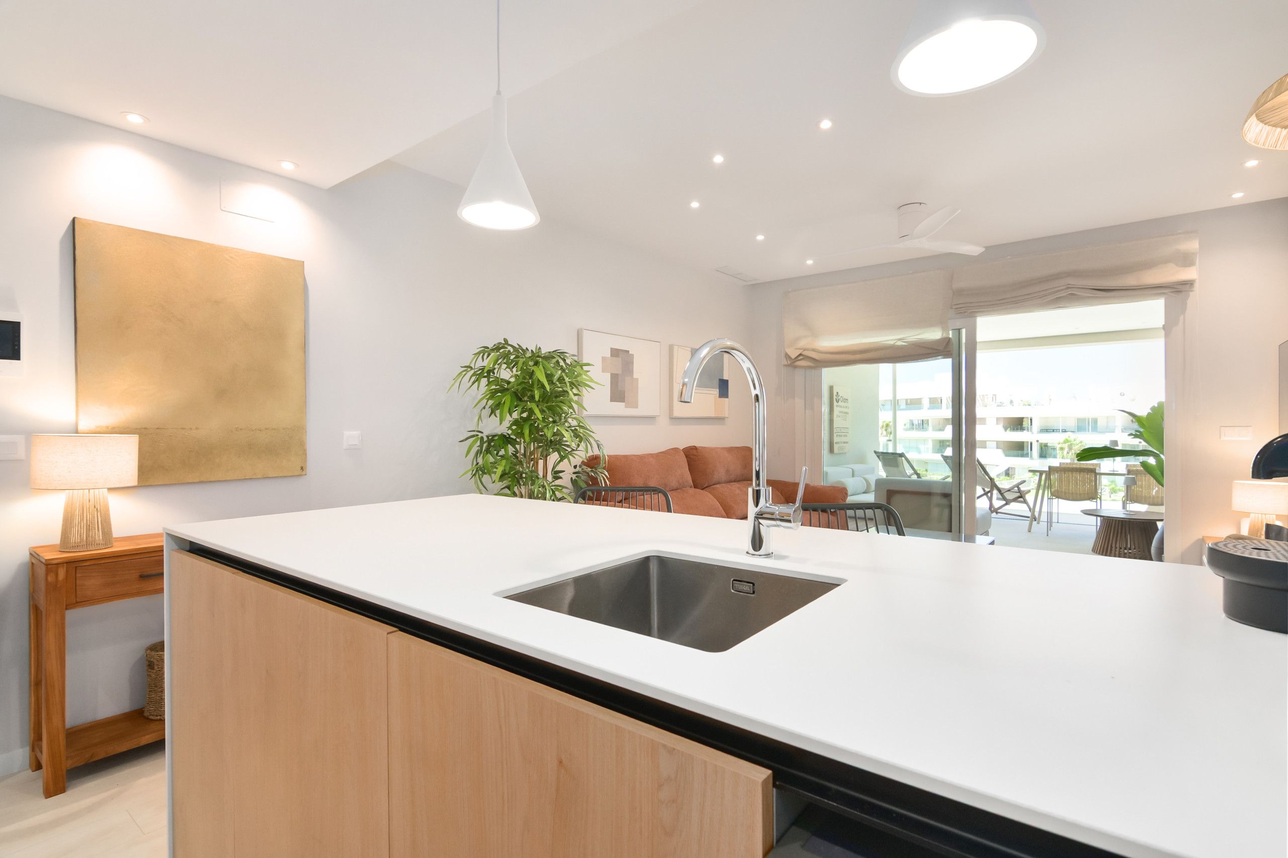 A modern kitchen with a central island, a sink, and a dining area with a table and chairs.