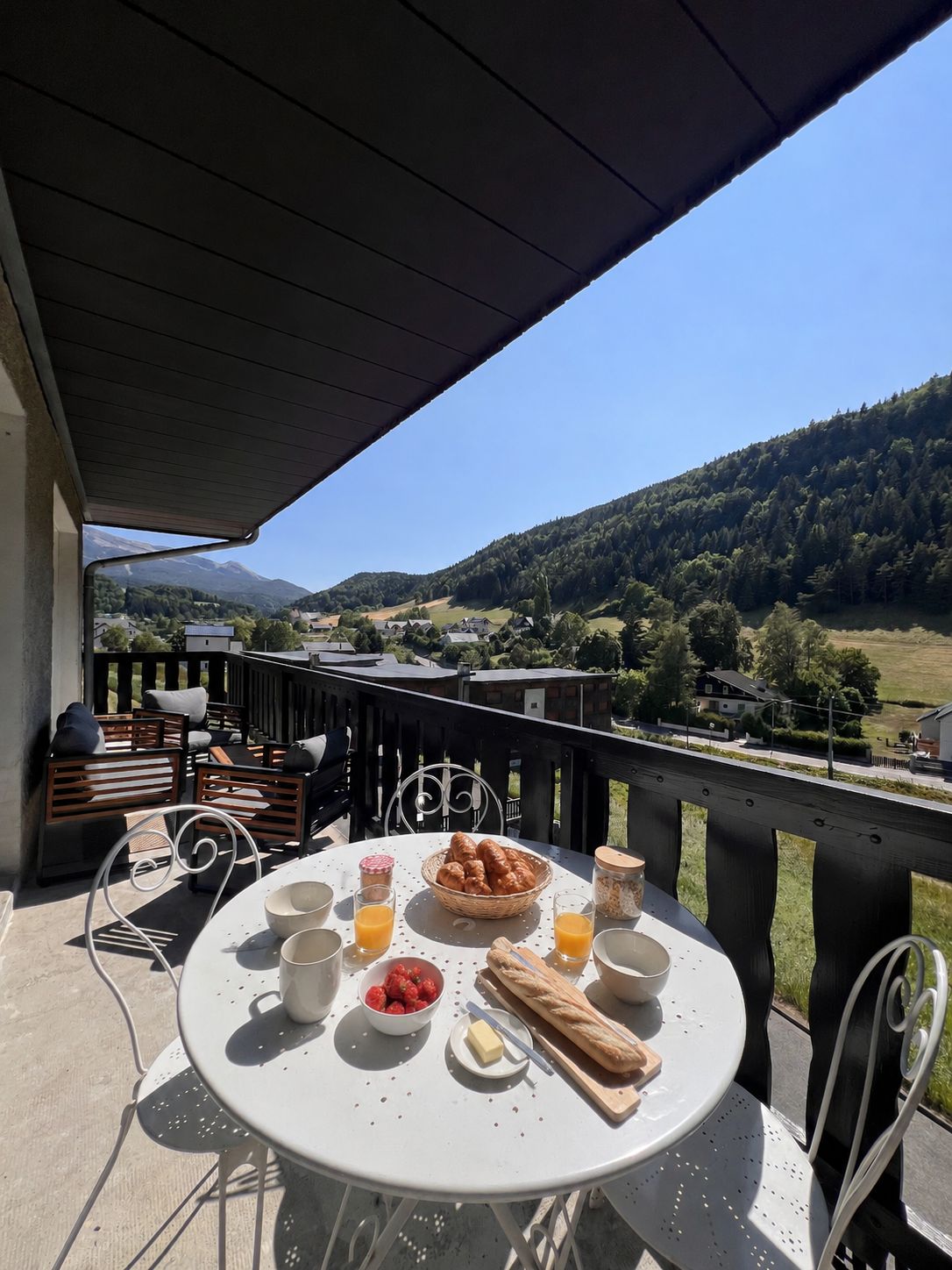 Mesa lista al aire libre con comida de desayuno, con vistas a un paisaje montañoso.