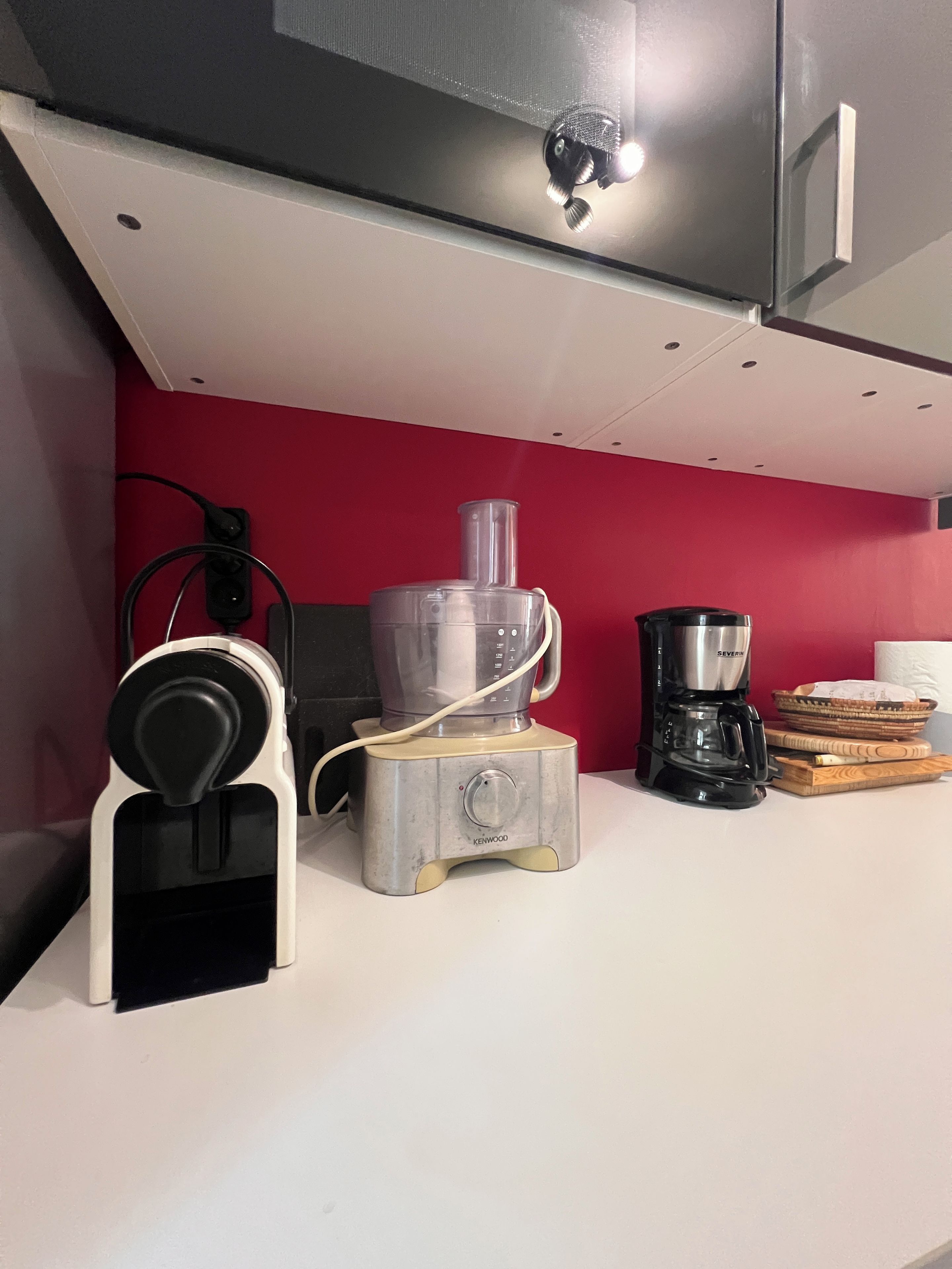 A kitchen with a coffee maker, a blender, and a kettle on the counter.
