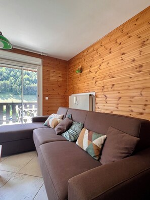 Un canapé marron avec plusieurs coussins, un radiateur et un mur en bois.