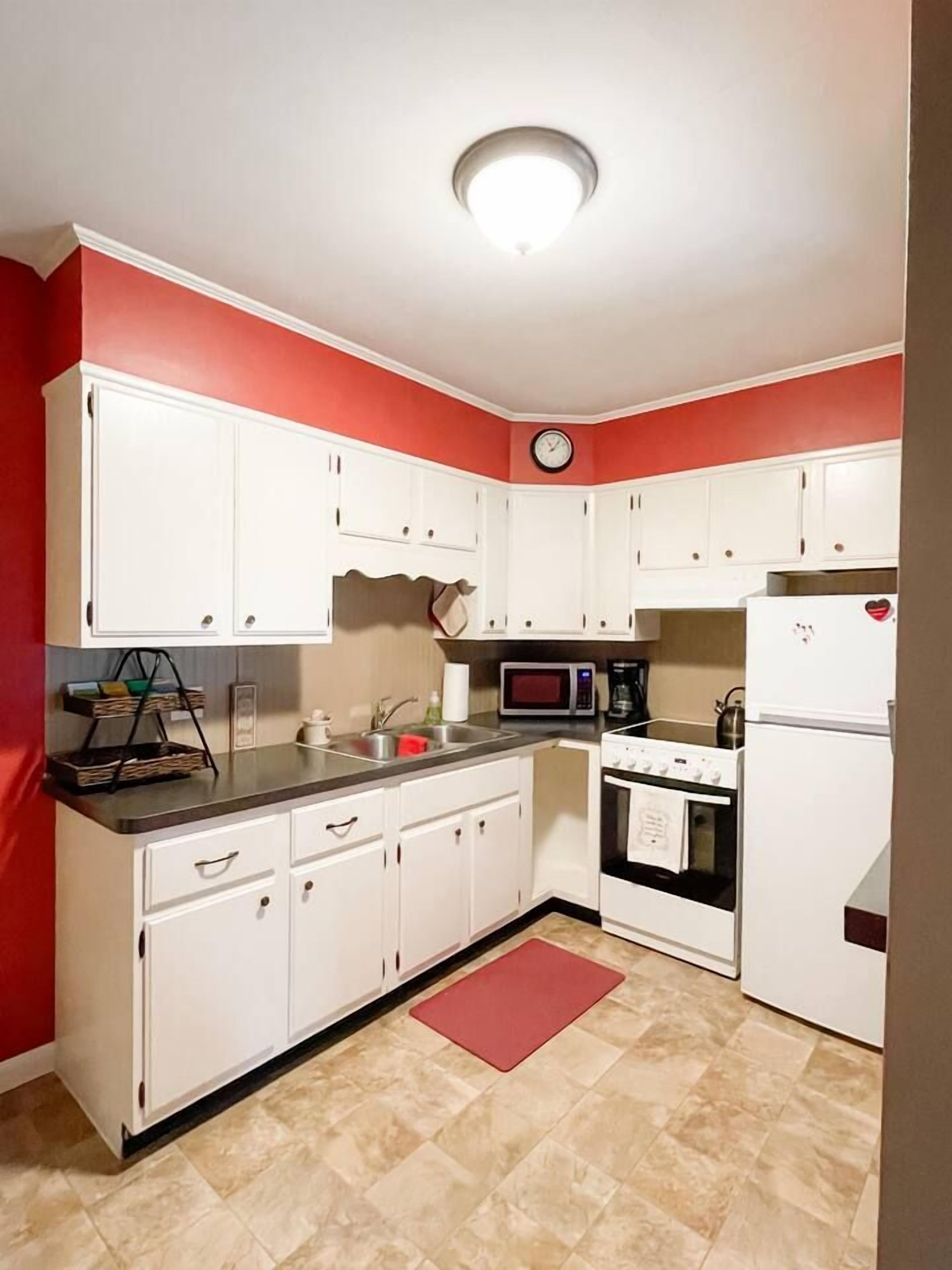 A compact kitchen with white cabinets, a microwave, a stove, and a refrigerator.