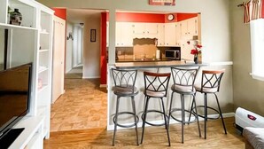 Una cocina moderna con barra, suelo de madera y televisor en la sala de estar.