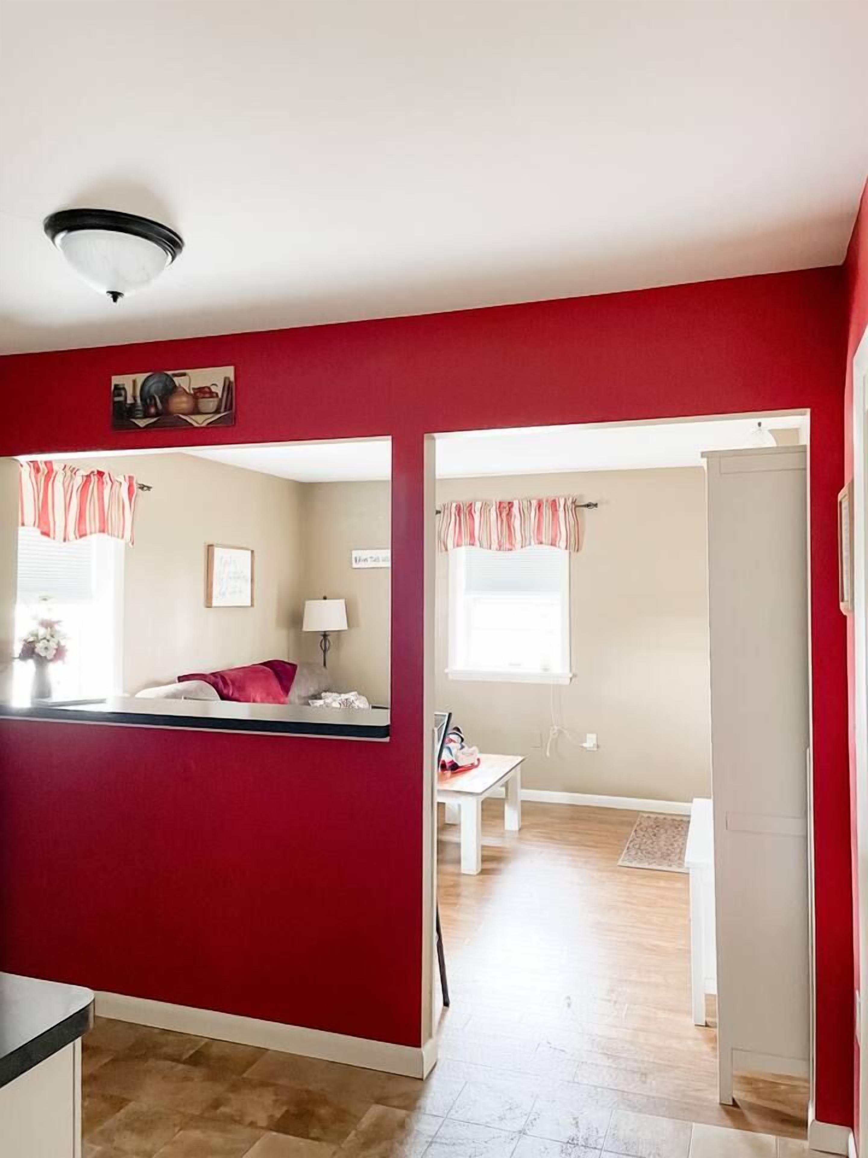 A room with a bed, a desk, a chair, a window with curtains, and a door.