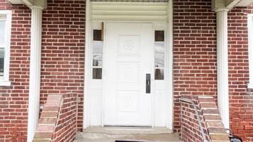 A brick house with a white front door, a set of concrete steps, and a small porch area.