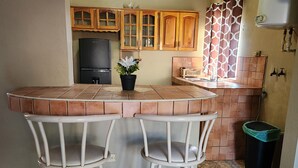 Una cocina con barra, armarios de madera, refrigerador y un cubo de basura.
