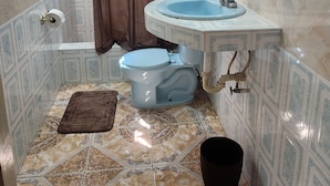 Un baño con inodoro, lavamanos y cortina de ducha.