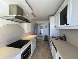 A narrow kitchen with white cabinets, a stainless steel range hood, a built-in oven, and a tiled floor. - Port Fréjus: magnificent 1-bedroom apartment with a harbor view, sleeping 4; lively area, air-conditioned, with Wi-Fi and parking. (Fréjus)