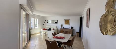 A modern living room with a dining area, a sofa, a coffee table, and a TV.