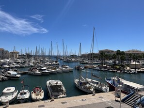 Un port de plaisance où sont amarrés de nombreux bateaux, un ciel dégagé et des bâtiments en arrière-plan.