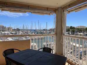 A balcony with a table and chairs, overlooking a marina with numerous boats and a clear blue sky. - Port Fréjus: magnificent 1-bedroom apartment with a harbor view, sleeping 4; lively area, air-conditioned, with Wi-Fi and parking. (Fréjus)