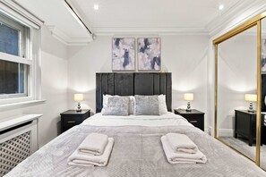 Ein Hotelzimmer mit einem großen Bett, zwei Nachttischen, einer Kopfteil und zwei abstrakten Bildern an der Wand.