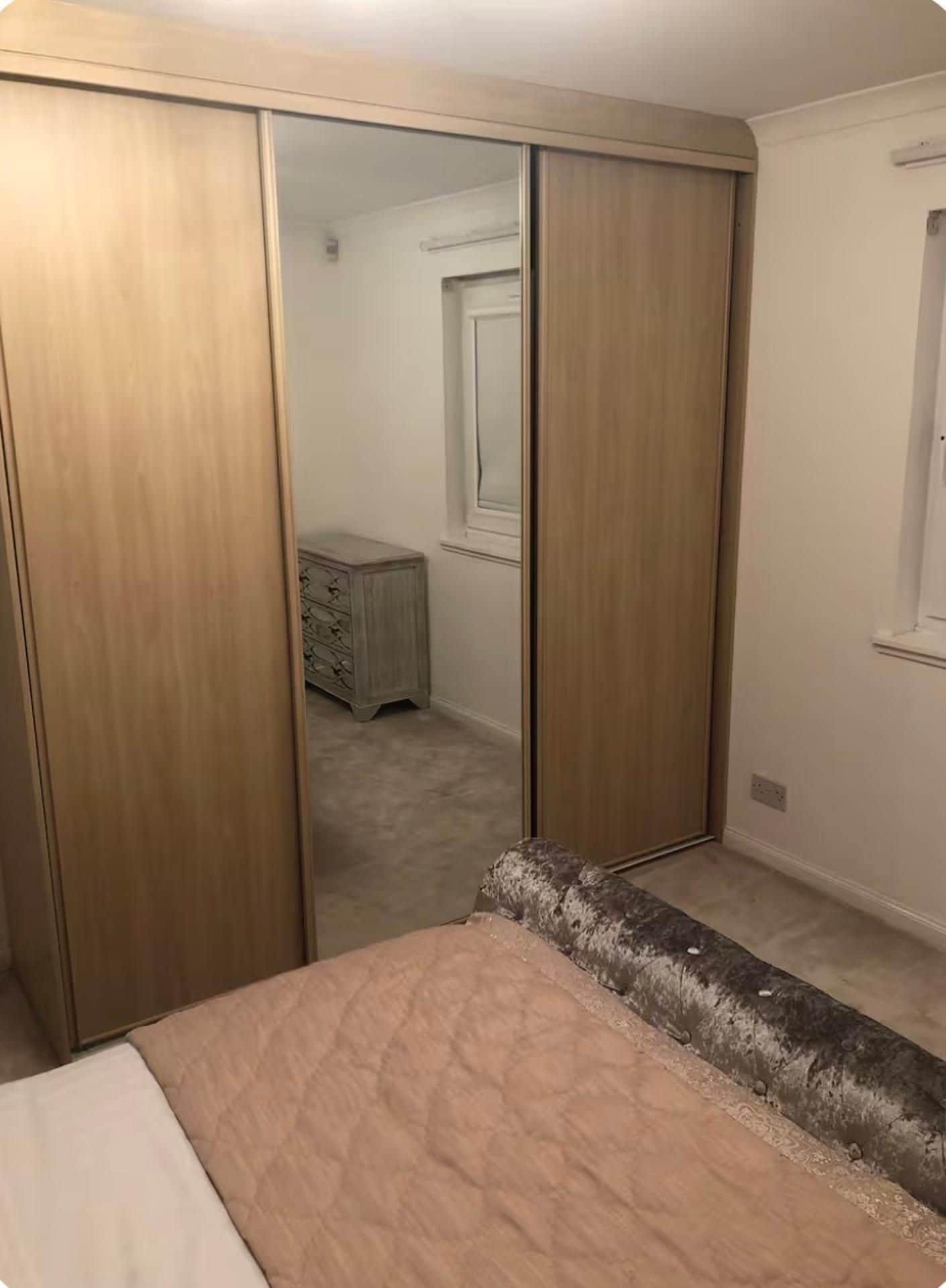 A bedroom with a bed, a wardrobe, and a dresser.