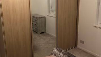 A bedroom with a bed, a wardrobe, and a dresser.