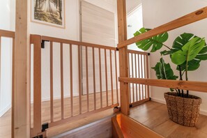 Eine Holztreppe mit Handlauf, einem Blumentopf und einer Tür im Hintergrund.