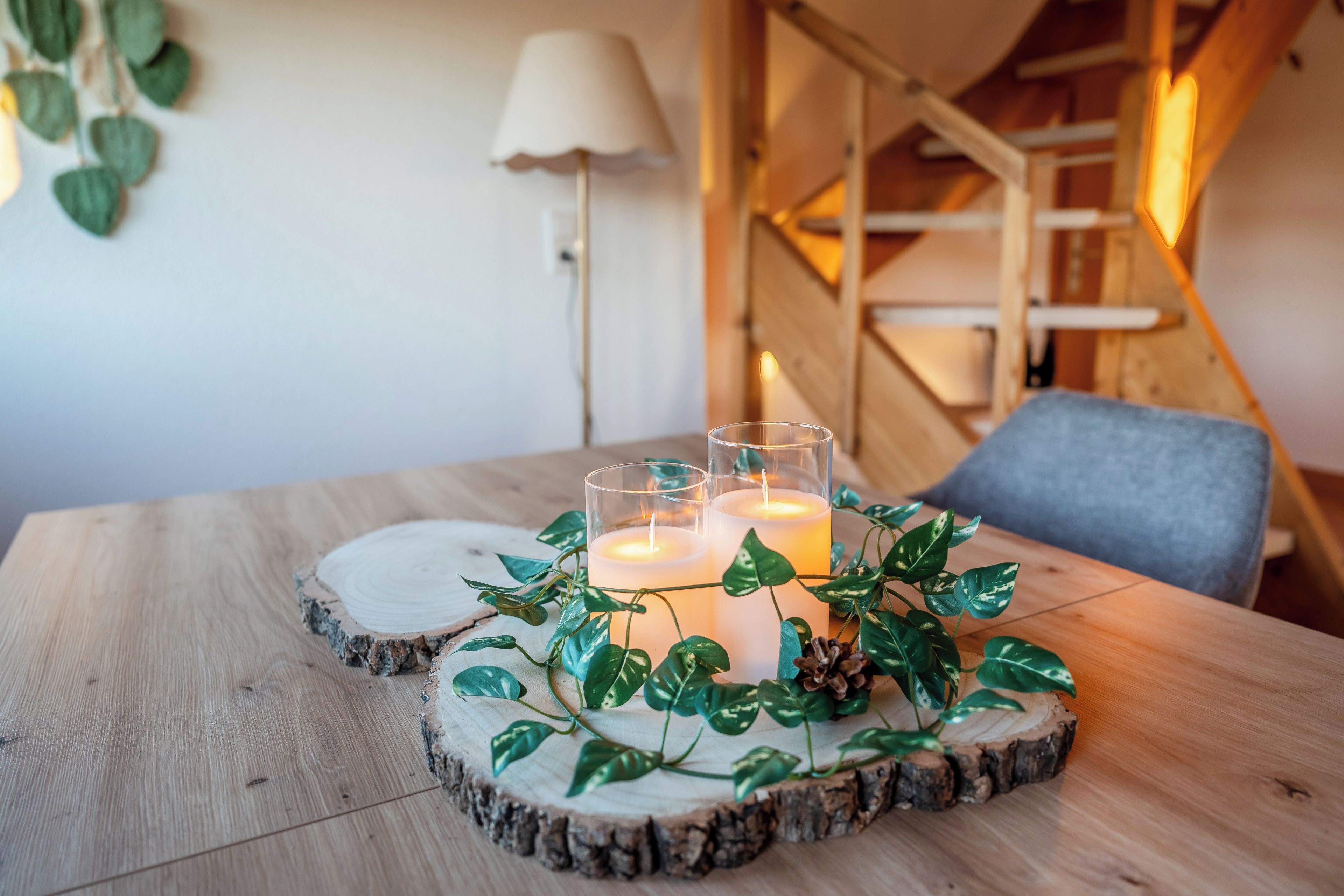 Una mesa de madera con un centro de velas rodeado de follaje.