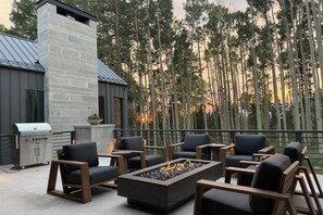 Une terrasse extérieure dotée d’une cheminée en pierre, de sièges et d’un barbecue.