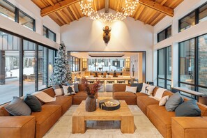 Un vaste espace de vie doté d’un grand plafond en bois, d’une table basse centrale et d’un sapin de Noël.
