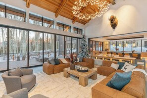 Un vaste espace de vie avec une grande fenêtre, un plafond en bois et un sapin de Noël.