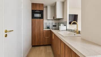 Une cuisine moderne avec des meubles en bois, un four encastré et un évier en acier inoxydable.