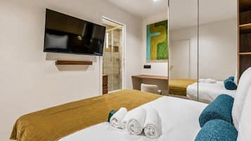 Une chambre d’hôtel avec un lit, un bureau, une télévision et un grand miroir.