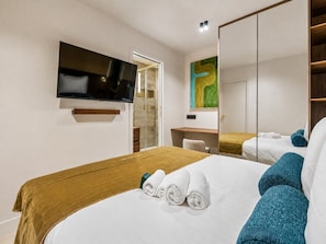 A hotel room with a bed, a desk, a television, and a large mirror.