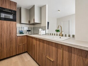 Une cuisine moderne avec des meubles en bois, un four encastré et un évier en acier inoxydable.