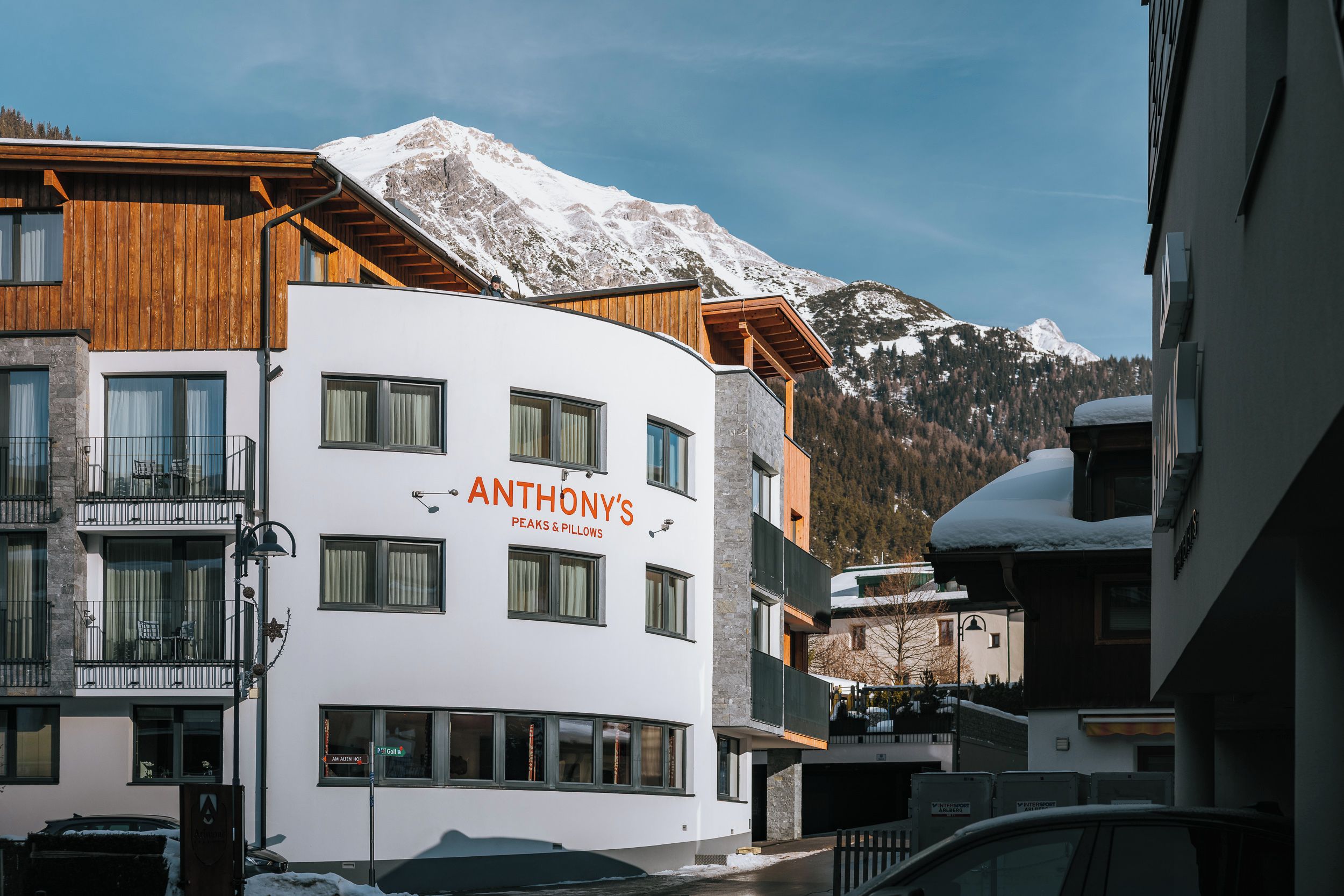 Ein Hotel namens 'Anthony's Peaks & Pillows' mit modernem Design, großen Fenstern und Blick auf schneebedeckte Berge.