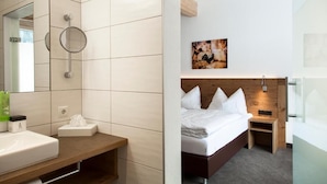 A hotel room with a large mirror, a wooden bedside table, a bed with white linens, a small bedside table, and a wall-mounted picture. - Anthonys Peaks and Pillows St Anton (Sankt Anton am Arlberg)