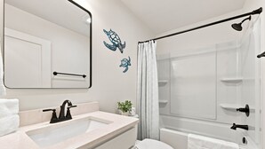 Ein Badezimmer mit Waschbecken, Spiegel, Toilette, Dusche und dekorativen Wandbildern.