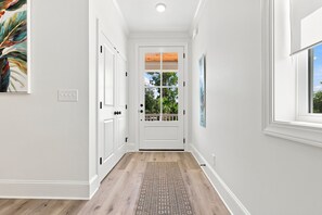 A hallway with white walls, a wooden floor, and a door with a view to the outside. - Choose Happiness Updated 4 BR short golf cart ride Pawleys Pet Friendly (Pawleys Island)