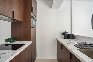 Eine moderne Küche mit Holzausstattung, einer weißen Arbeitsplatte und einem eingebauten Herd.