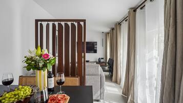 Een moderne hotelkamer met een eetgedeelte, een houten scheidingswand en uitzicht op de stad.