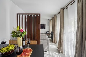 Ein modernes Hotelzimmer mit Essbereich, einer Holzwand und Blick auf die Stadt.