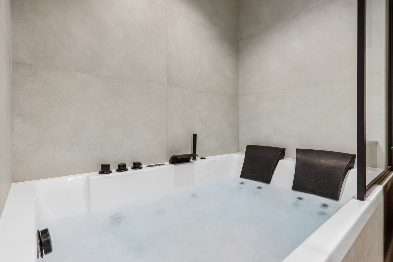 Ein modernes Badezimmer mit einer großzügigen Badewanne, einer Duschkabine aus Glas und einem minimalistischen Design.