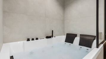 Une salle de bain moderne dotée d’une grande baignoire, d’une douche à parois de verre et d’un design minimaliste.