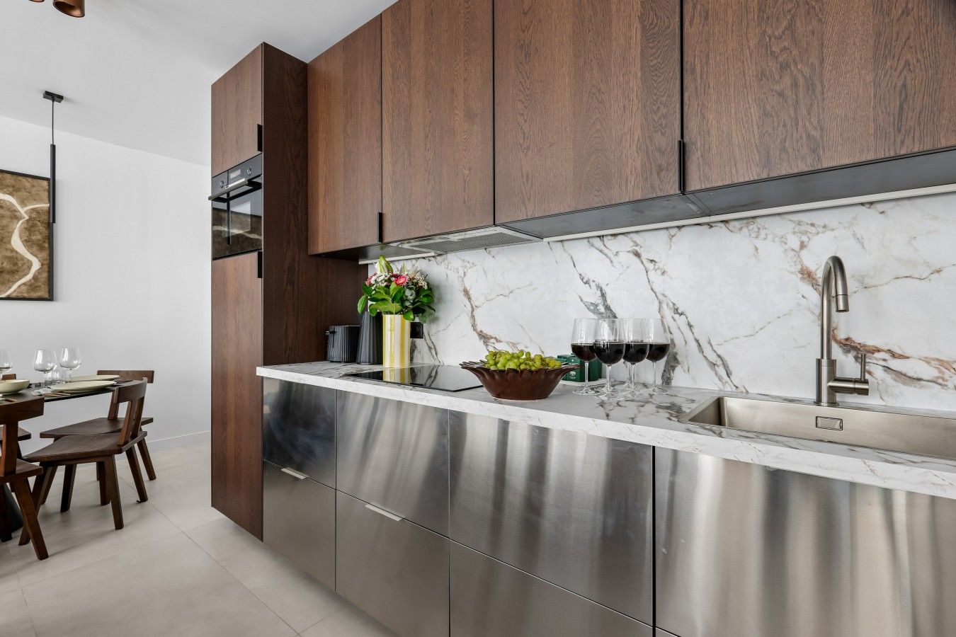 A modern kitchen with stainless steel appliances, wooden cabinets, and a marble backsplash.