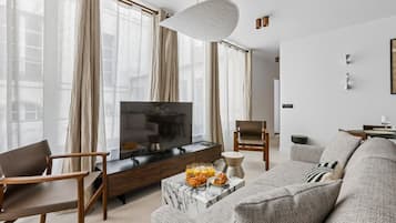 Un salon moderne avec un téléviseur, des sièges et une table basse.
