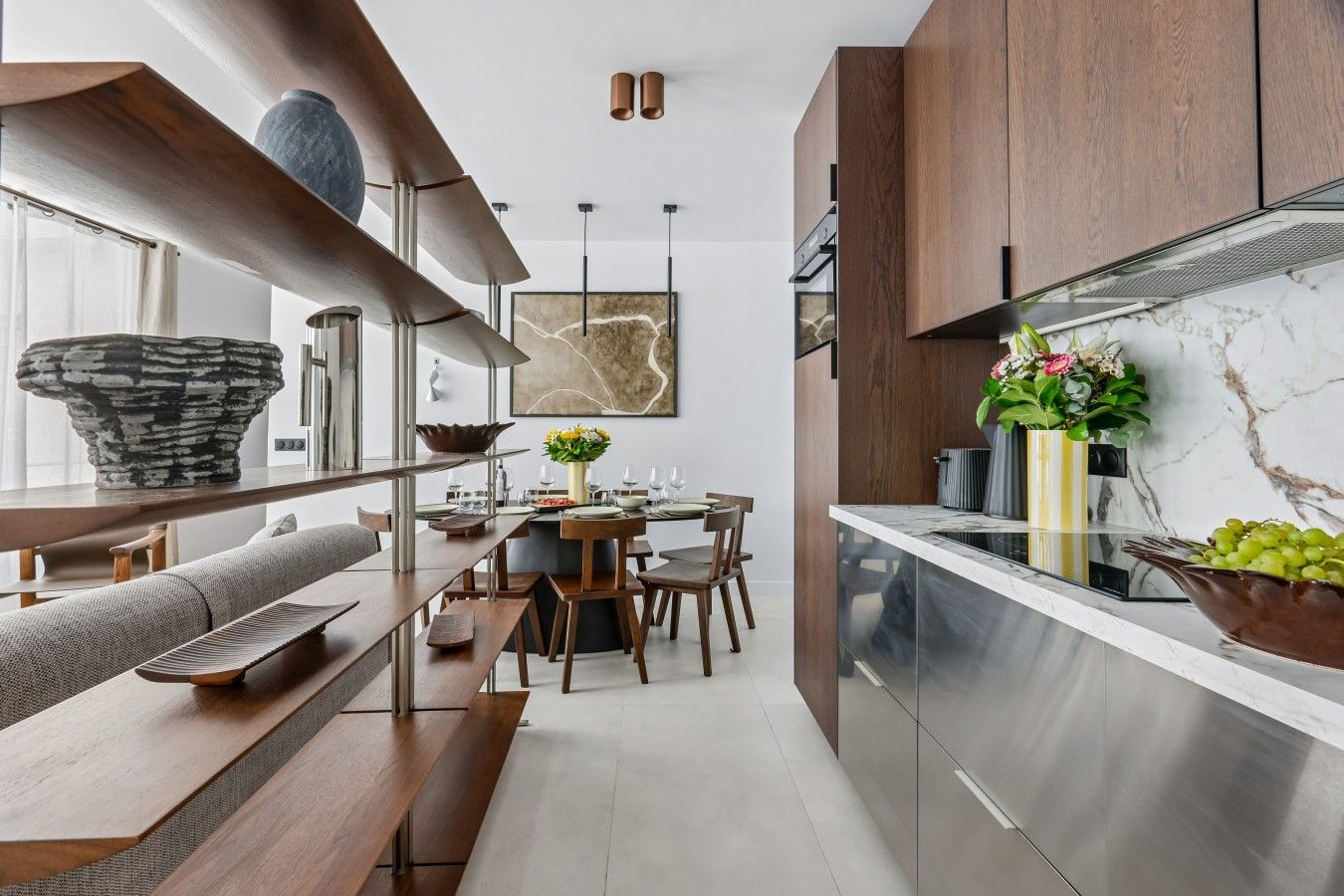 Een moderne keuken met een marmeren aanrechtblad, houten kastjes en een eethoek met een bank en tafel.