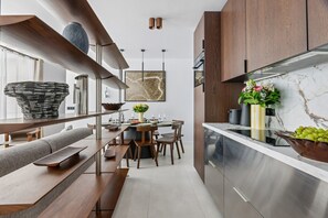 A modern kitchen with a marble countertop, wooden cabinets, and a dining area with a bench and table.