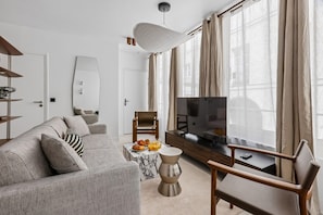 Ein modernes Wohnzimmer mit einer Couch, einem Couchtisch, einem Fernseher und einem Sessel.