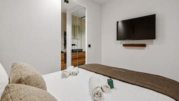 Une chambre d’hôtel avec un lit, un téléviseur à écran plat fixé au mur et un miroir qui reflète la pièce.