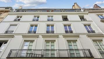 Un immeuble à plusieurs étages, doté d’une façade symétrique, de grandes fenêtres et d’un balcon orné de rampes en métal.