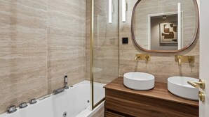 Ein modernes Badezimmer mit einer Badewanne, zwei Waschbecken, einem großen Spiegel und einer Holzausstattung.