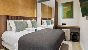 Ein modernes Schlafzimmer mit einem großen Bett, einem Nachttisch, einem Sessel, einem Spiegel und einem Bild an der Wand.