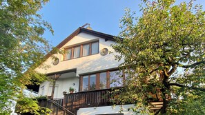 A two-story house with a balcony, a wooden fence, and a tree in the foreground. - Bergulme Vacation Rental with a View of the Tyrolean Mountains (Mutters)