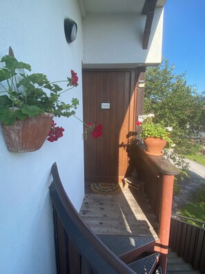 A wooden door with a 'Welcome' mat, a potted plant on the wall, and a small bench with a lantern. - Bergulme Vacation Rental with a View of the Tyrolean Mountains (Mutters)